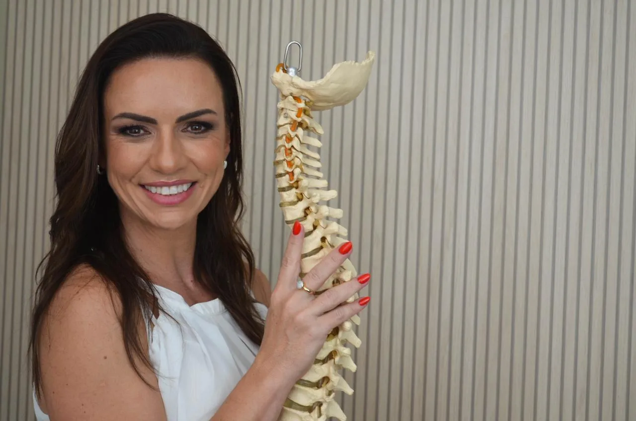 Paula segurando um modelo anatômico da coluna vertebral